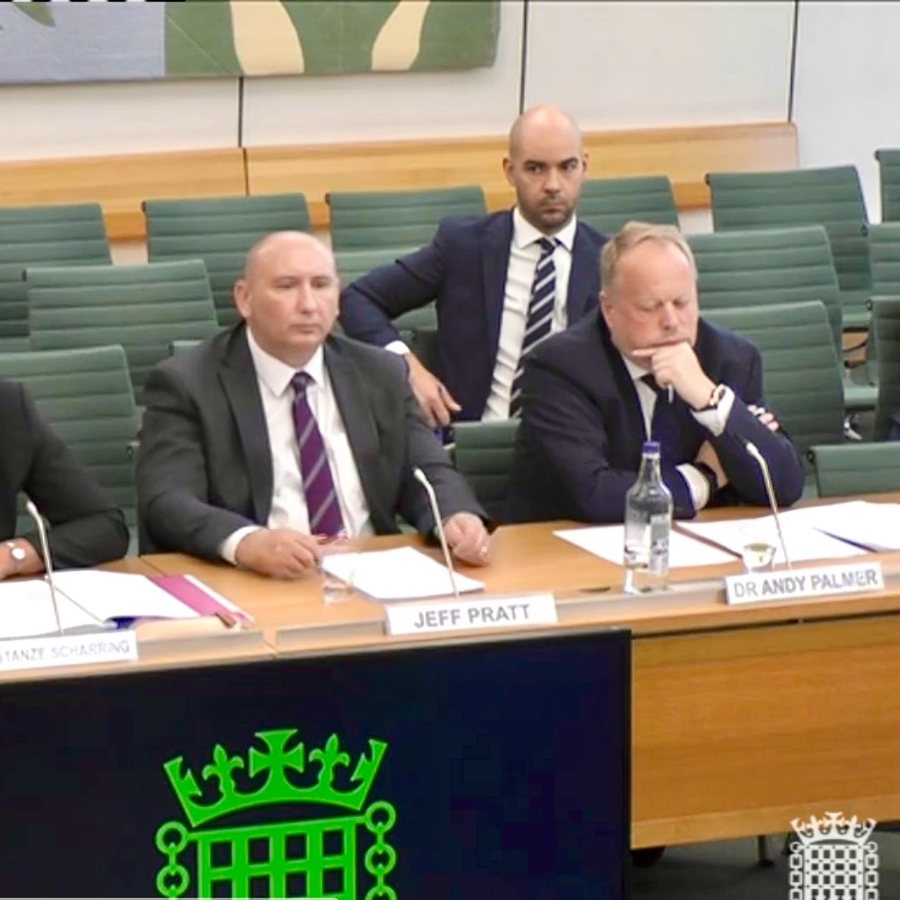 Leon Emirali behind Dr Andy Palmer at a House of Commons select committee hearing