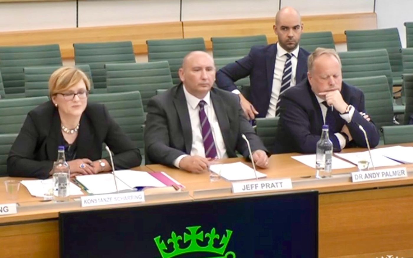 Leon Emirali behind Dr Andy Palmer at a House of Commons select committee hearing