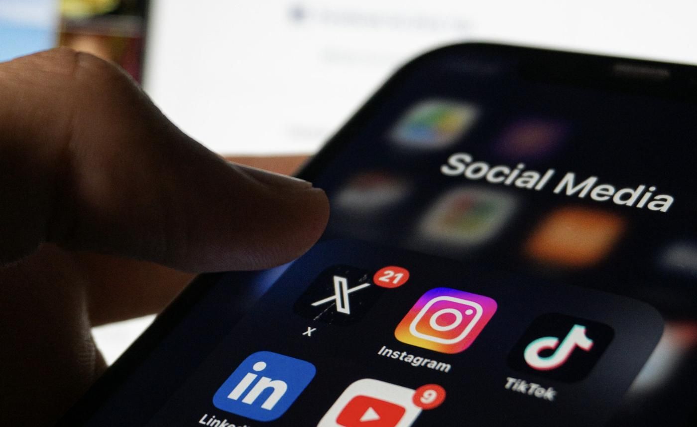 A hand holding a phone showing social media apps